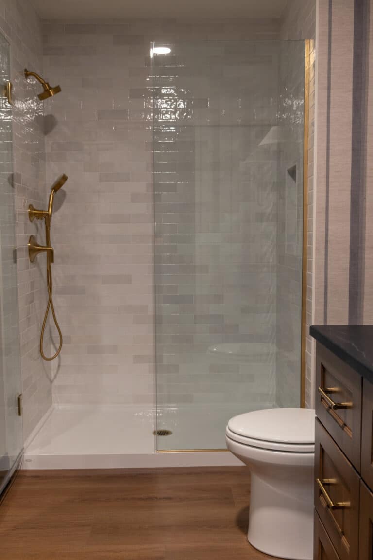 walk in shower with glass enclosure and white and grey tile shower wall