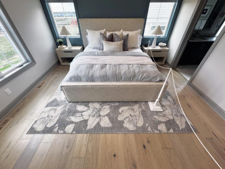 hardwood floor with a custom area rug under a queen bed