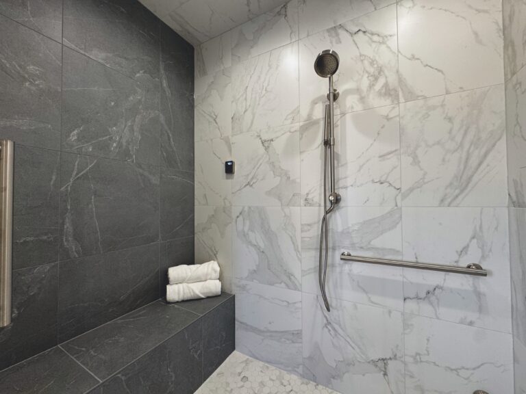 walk in shower with grey marble tile bench and white marble tile walls