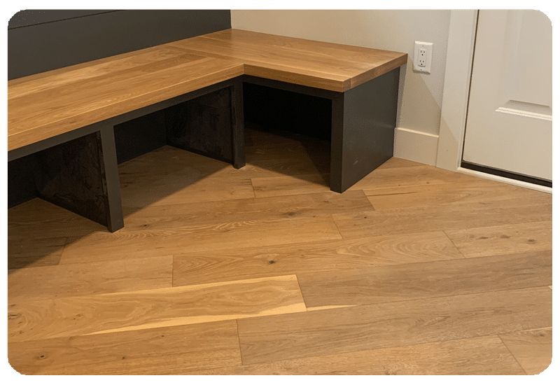 Warm wide-plank hardwood floor meeting a custom built-in wood bench and storage nook